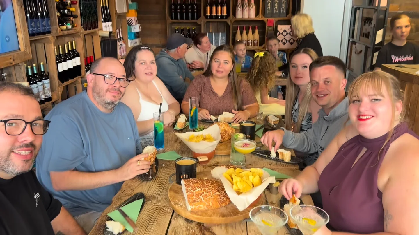 Friends smiling around a table with fondue, nachos and cocktails