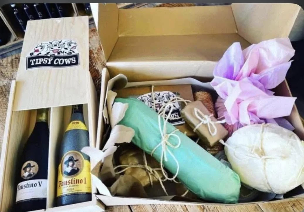 An open Tipsy Cows hamper with cheeses and bottles