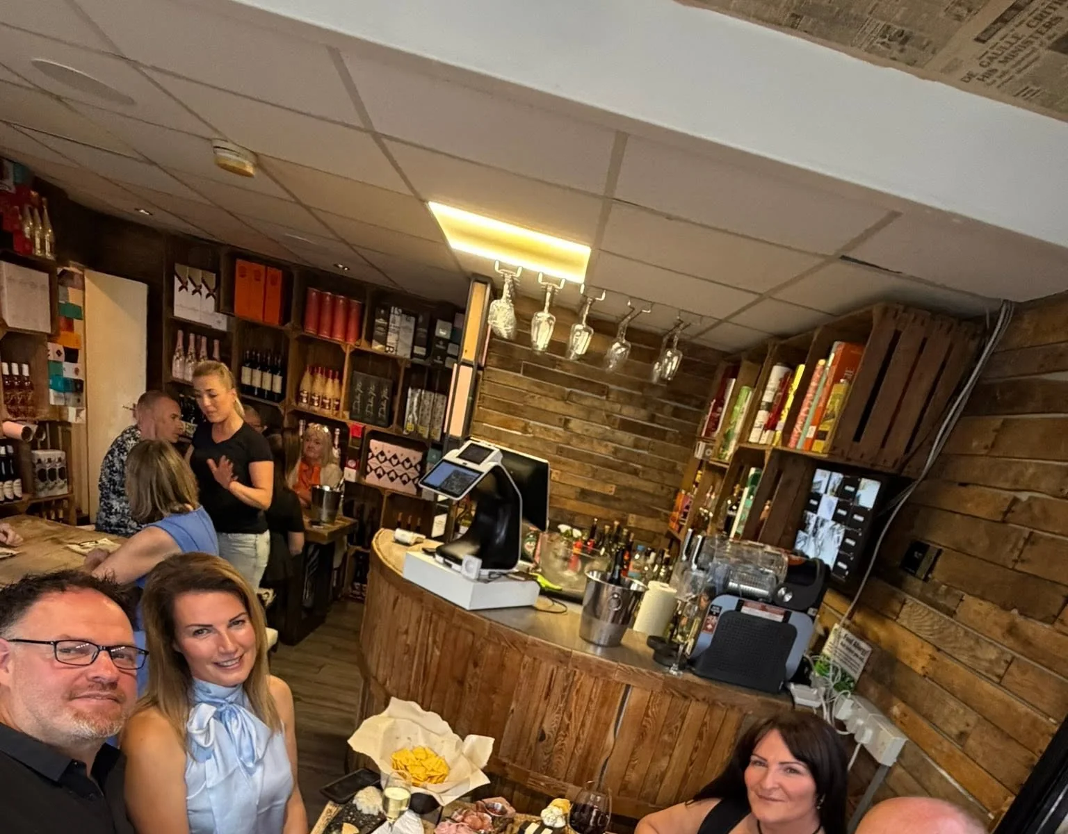 The Tipsy Cows bar, with wine crates, hanging glasses and the team at the counter