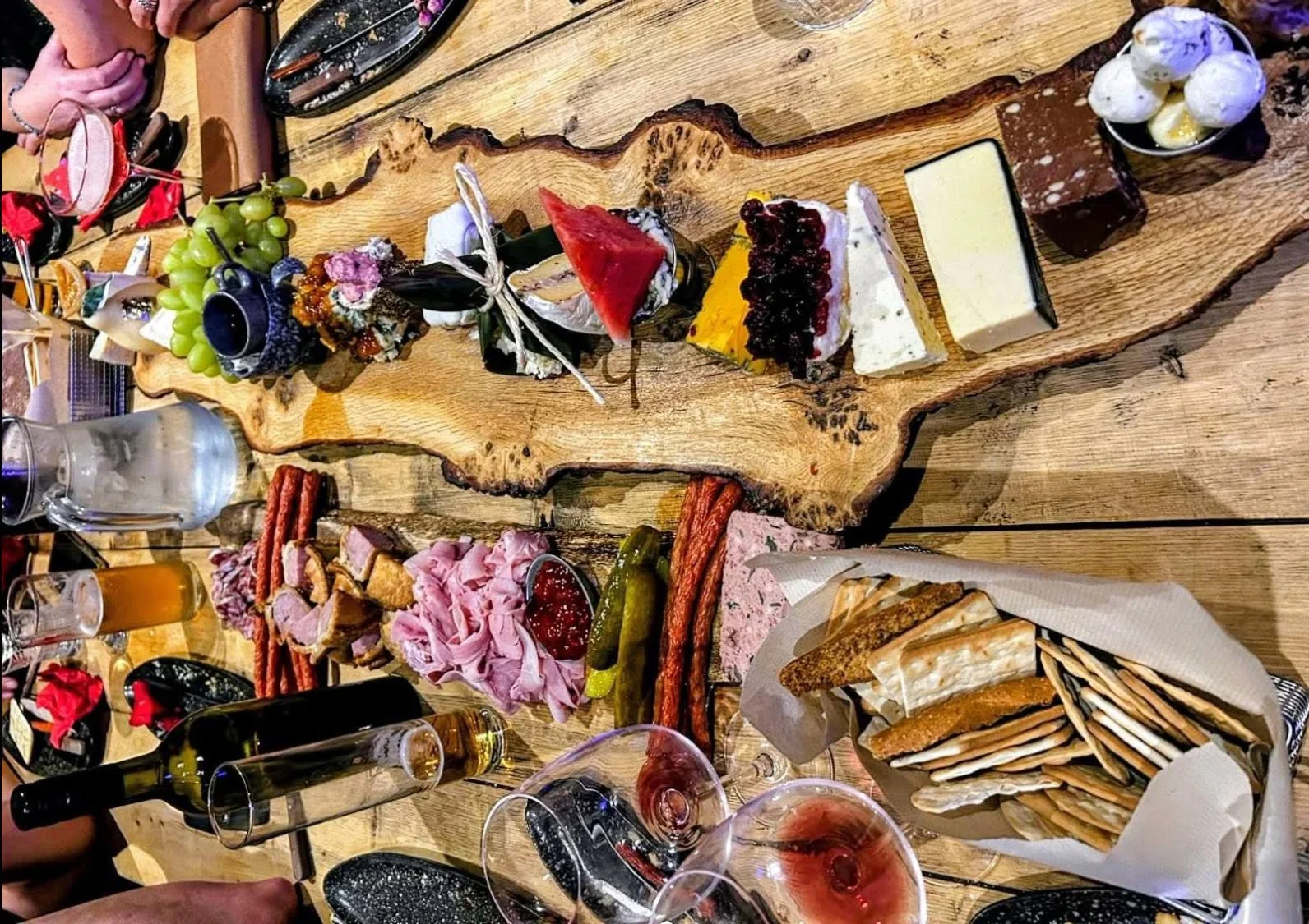 A long live-edge board of artisan cheeses, watermelon, grapes, cured meats and crackers