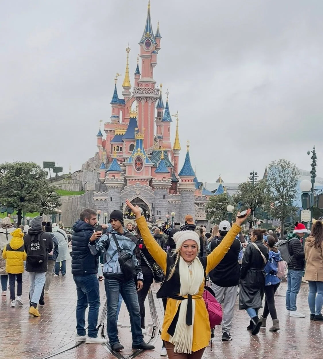 Arms raised in celebration in front of the castle on a Nothing Is Impossible trip to Disneyland Paris