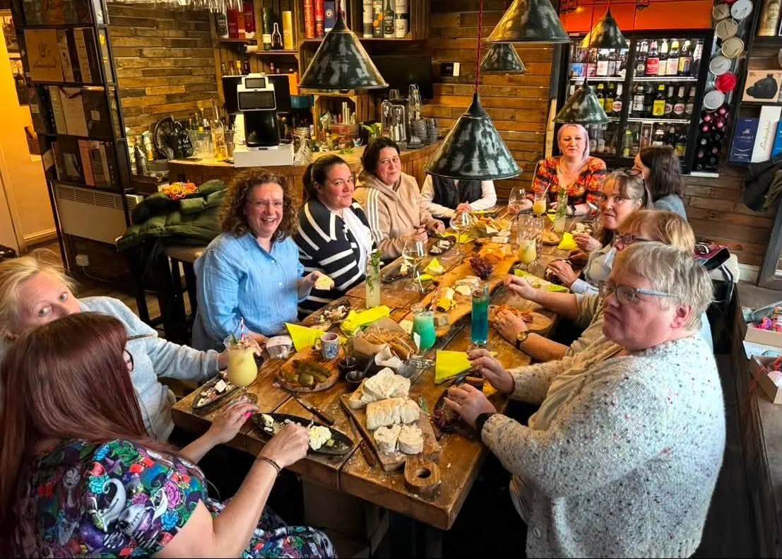 Friends around a long table of sharing boards and cocktails at Tipsy Cows