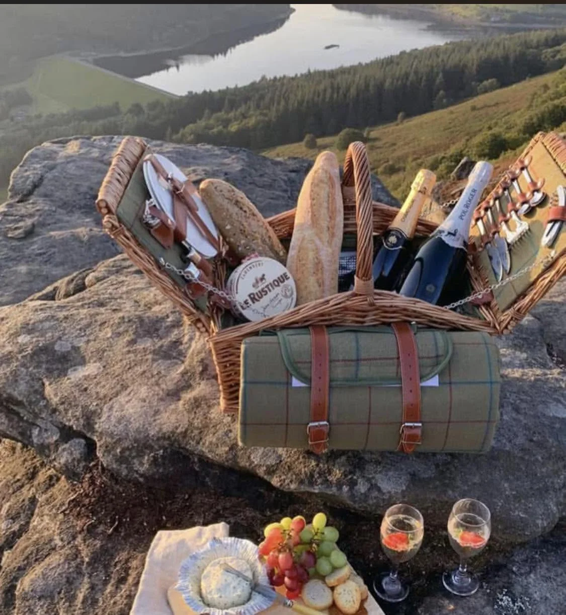 A Tipsy Cows picnic basket hamper with bread, cheese and fizz on a moorland edge