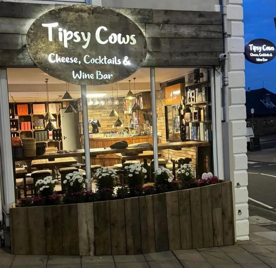 The Tipsy Cows shopfront on Church Street at dusk, its sign reading Cheese, Cocktails & Wine Bar