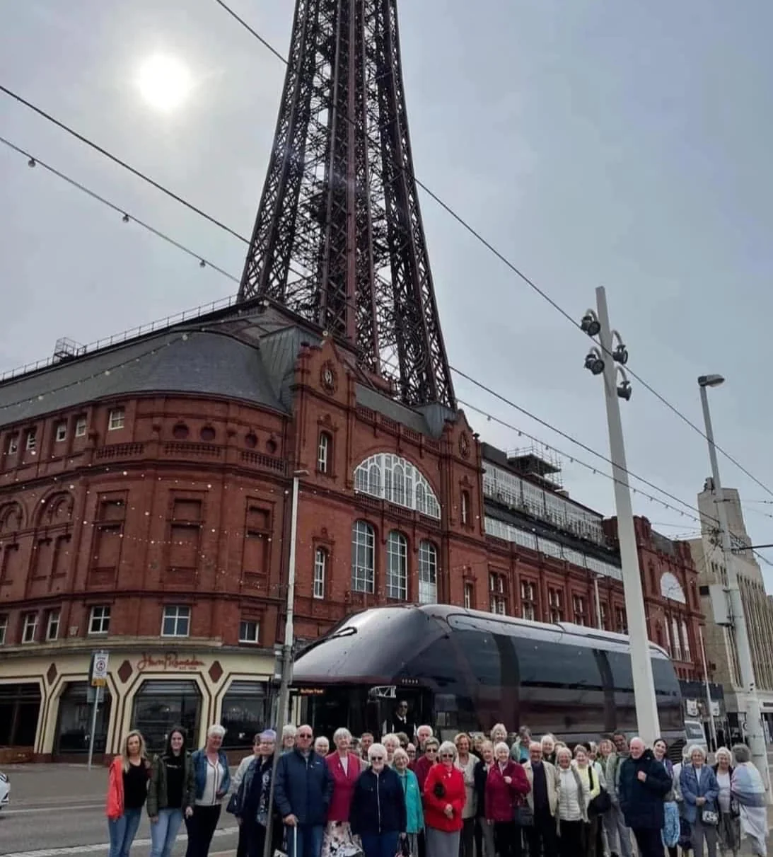 A large group on a Nothing Is Impossible pensioners’ day out beneath Blackpool Tower