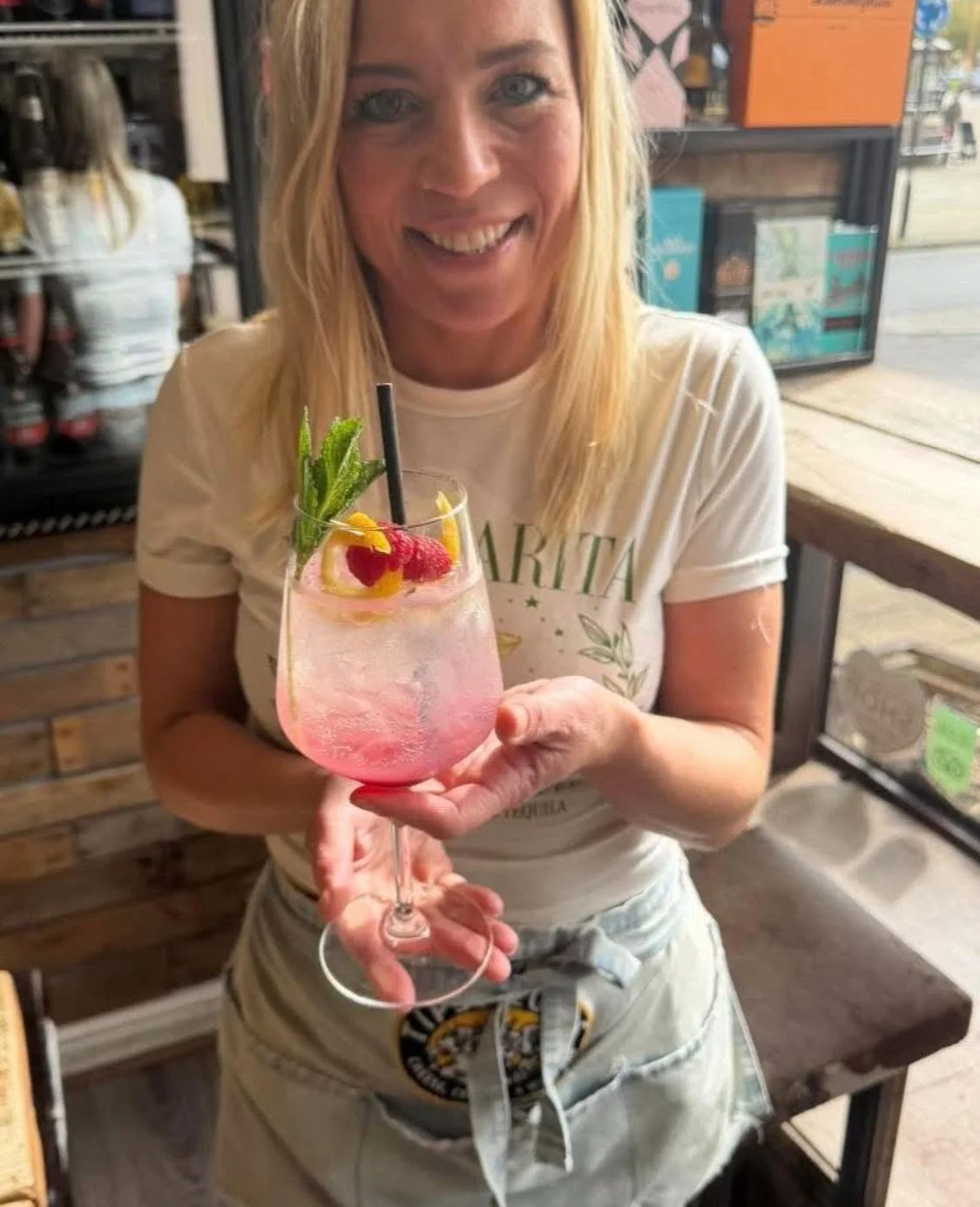 A guest holding a pink cocktail with a strawberry garnish at Tipsy Cows