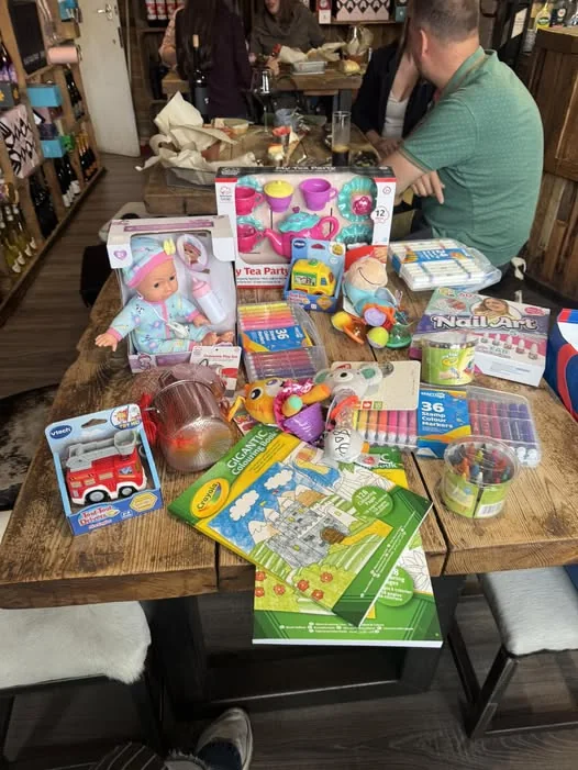 Donated toys and craft sets piled on a Tipsy Cows table for the Christmas toy appeal